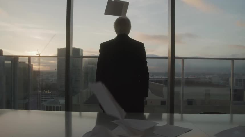 Man in suit in a panoramic office room of a building throwing papers up