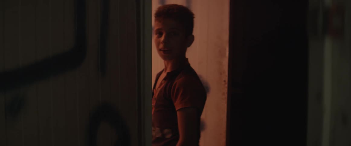 A young boy walks into a doorway and turns to look back