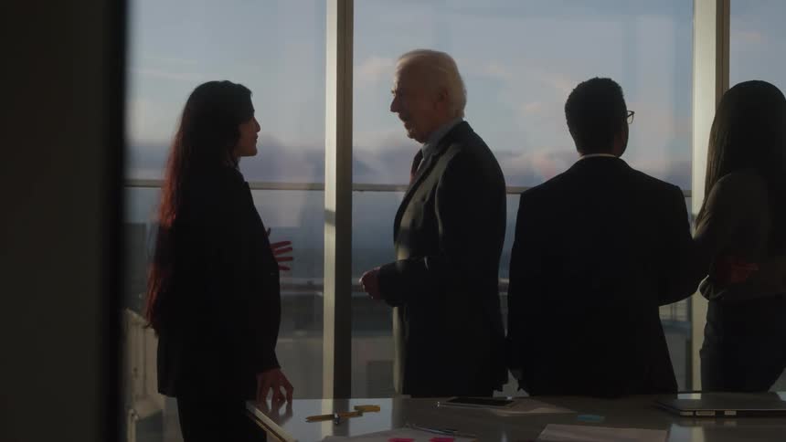 Group of executives talking near a window overlooking the city at sunset