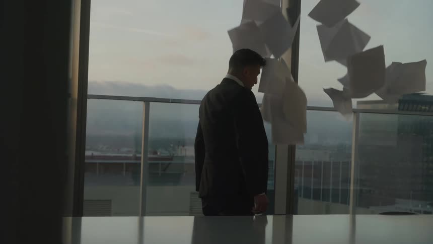 Man in suit throws sheets of paper that fly around him