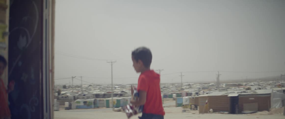 A boy runs towards a house with items in his hands