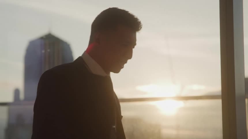 A young man in his office at sunset going through some documents suddenly becomes angry and tosses all the papers into the air causing them to fly abruptly