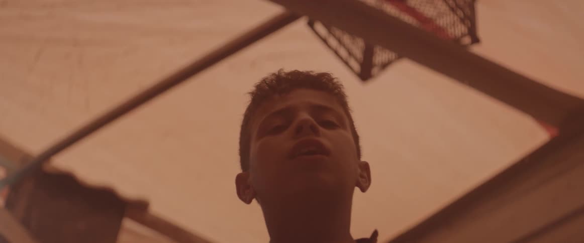 A young boy stands in a shelter with a canvas ceiling