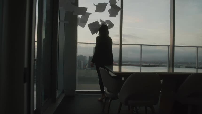 Woman in an office room and throwing papers up