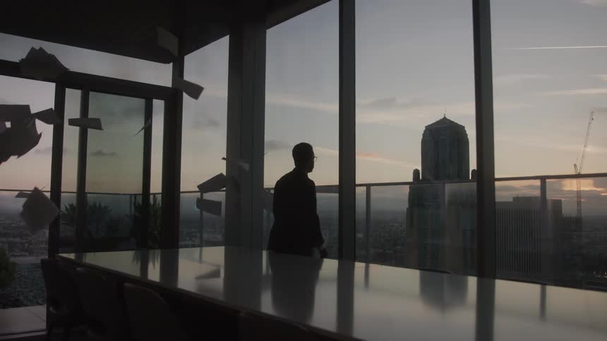 Silhouette of a man in a suit in an office room throwing papers up