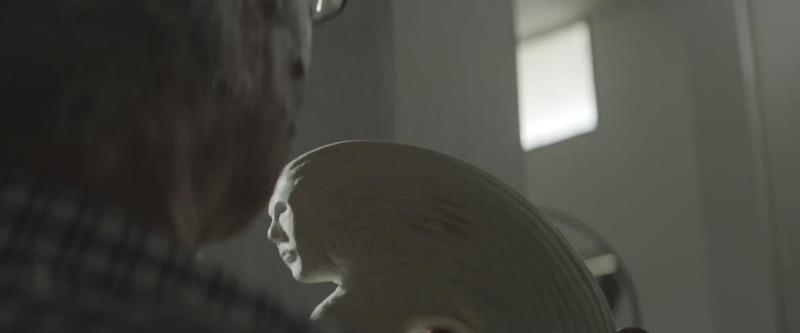 A man inspects a wooden carving