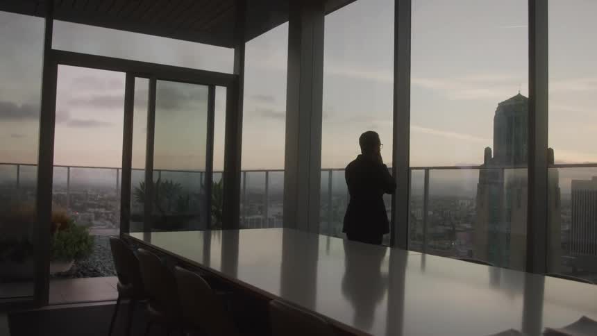 Man walking in an office room with a panoramic view of a city