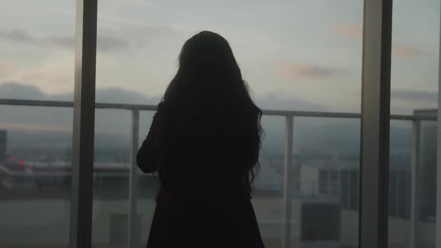 Woman in blazer walking back and forth in an office
