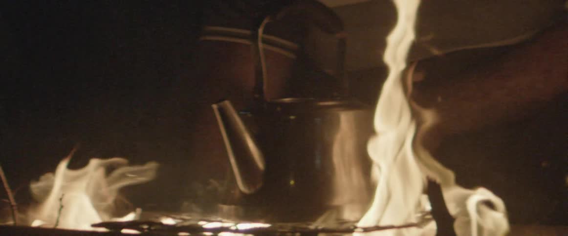 Fire burns high at night around a pot