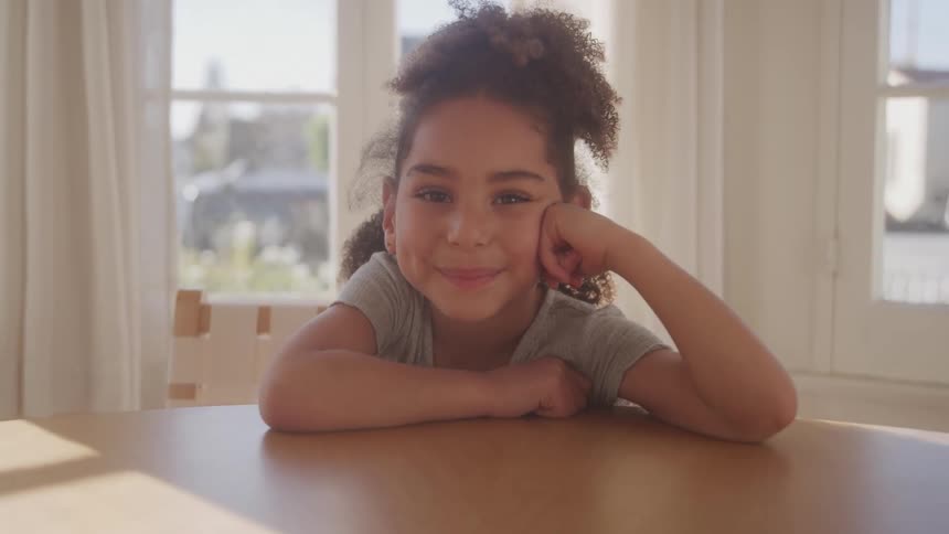 The girl is smiling while seated at the table