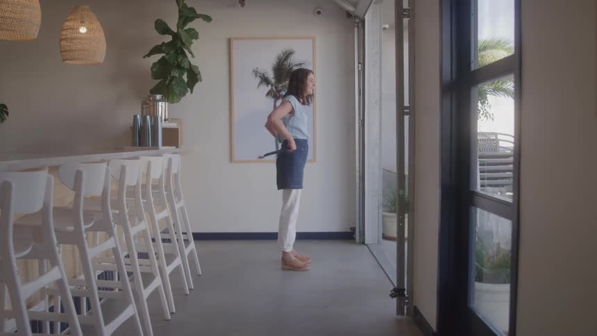 Woman inside a coffee shop adjusting her apron around her waist