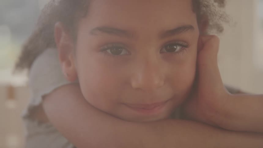 Little girl with her face resting on her arm with a happy expression