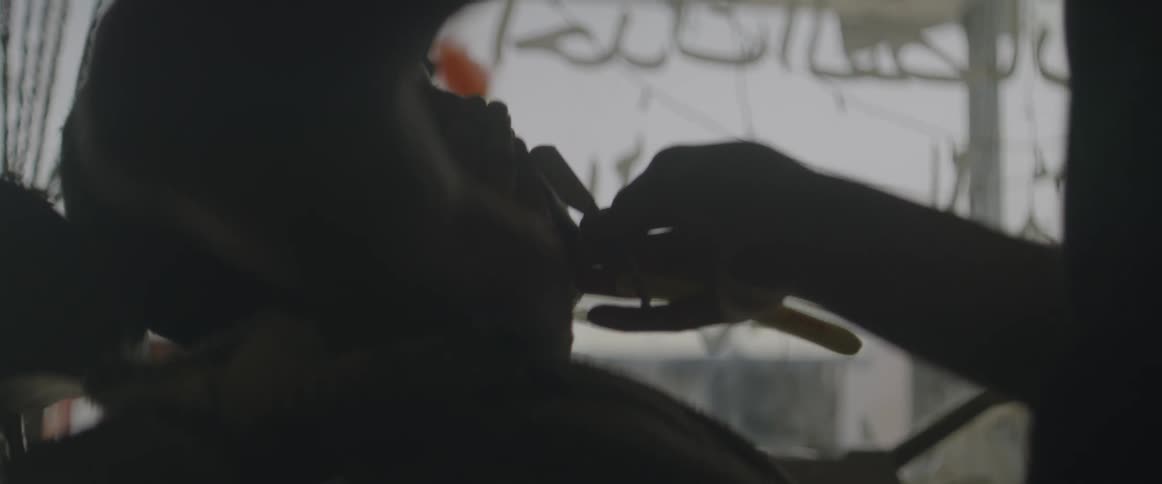 A barber shaves a mans beard