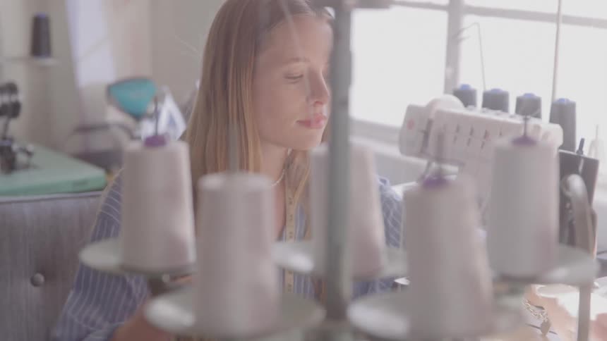 Blonde woman sitting working in front of a sewing machine