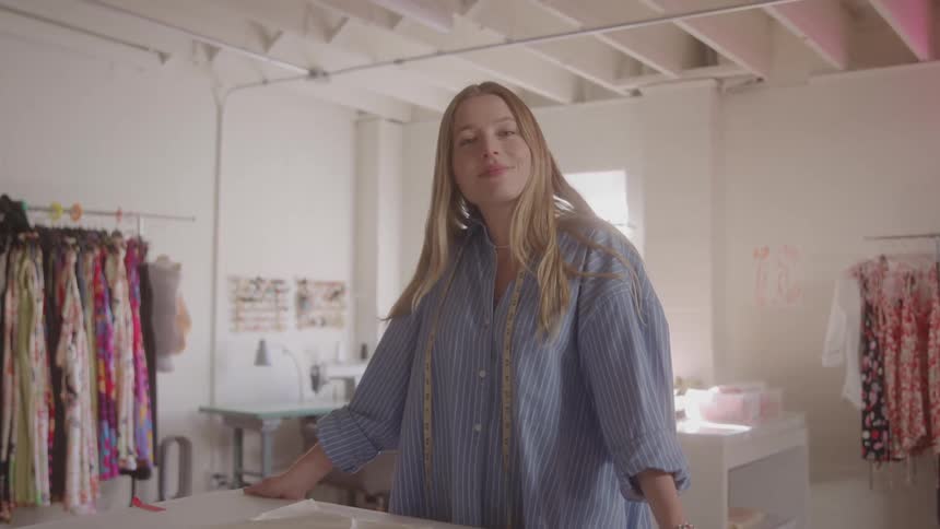 A woman stands confidently in a brightly lit fashion studio