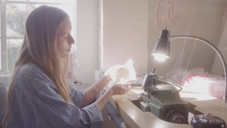 Woman sews with machine in bright workspace