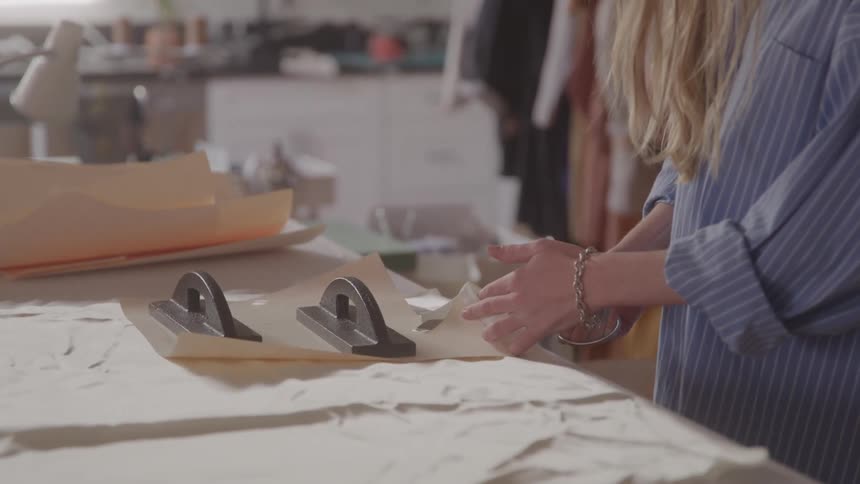 The tailor is using a scissor on clothing