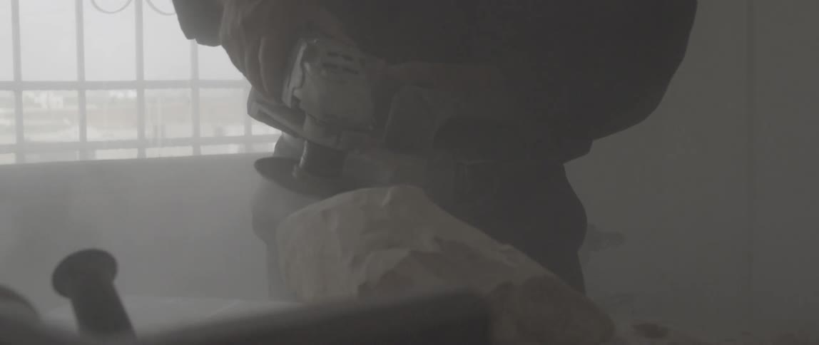 Man using a sander on a chunk of rock