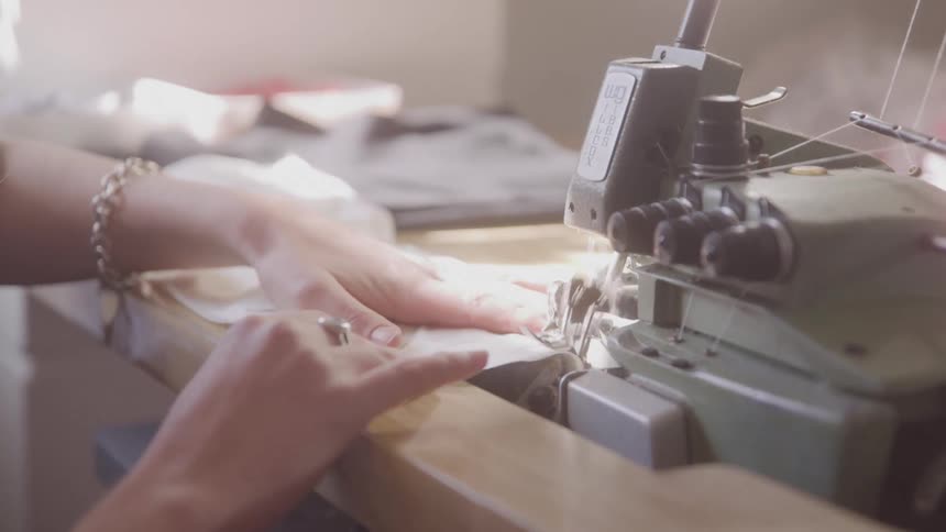 Pair of hands sewing a fabric on a machine