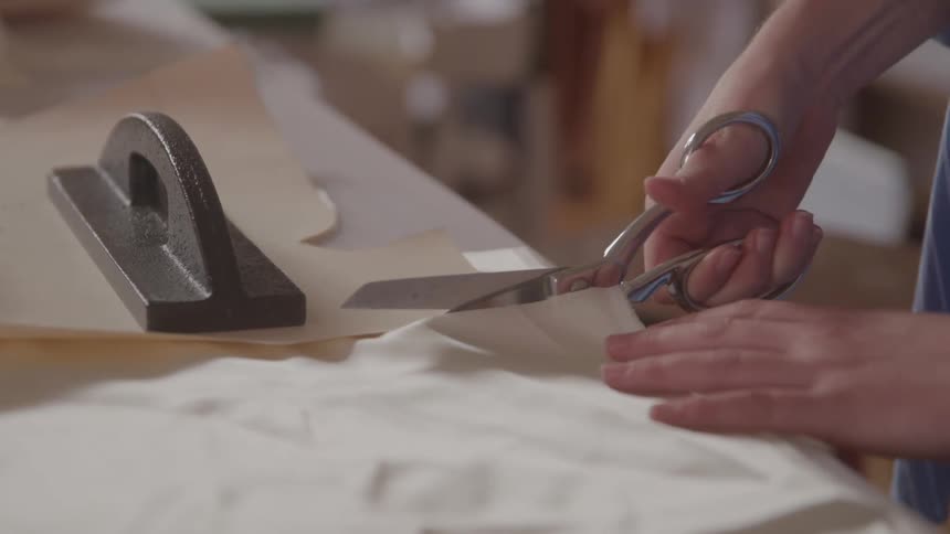 Person cuts fabric with large scissors in textile workspace