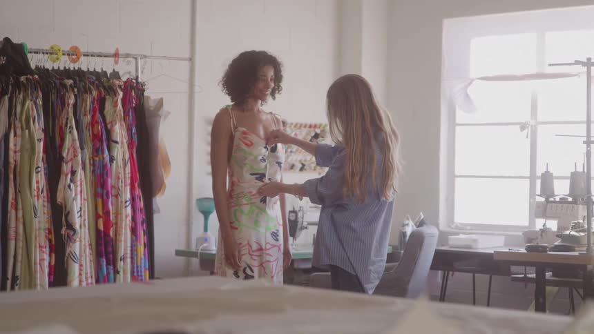 Fashion designer measures client in bright studio
