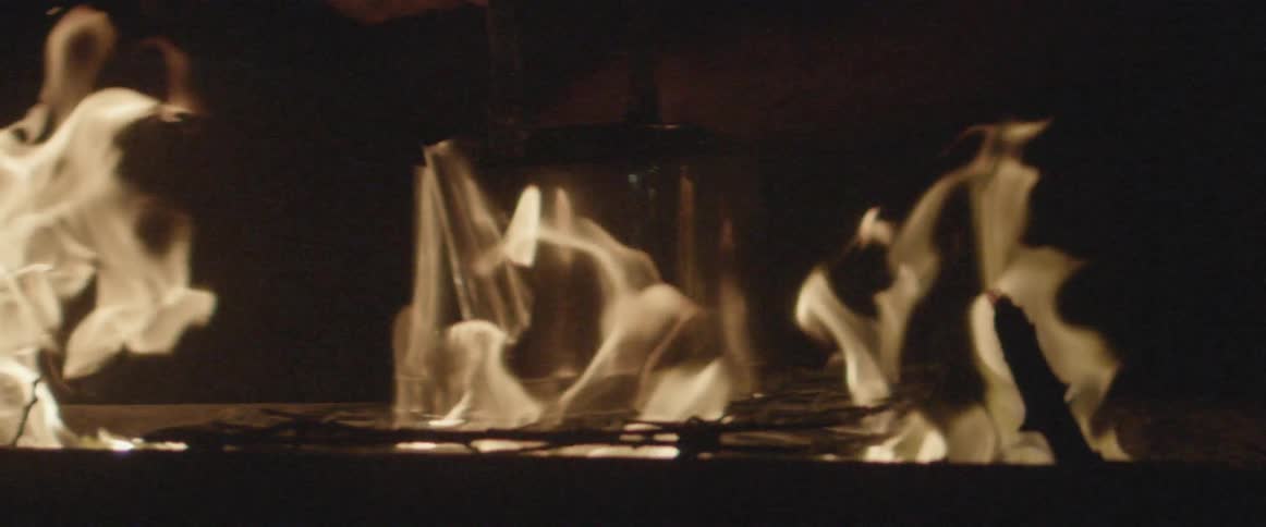 A pot is cooking over a large fire