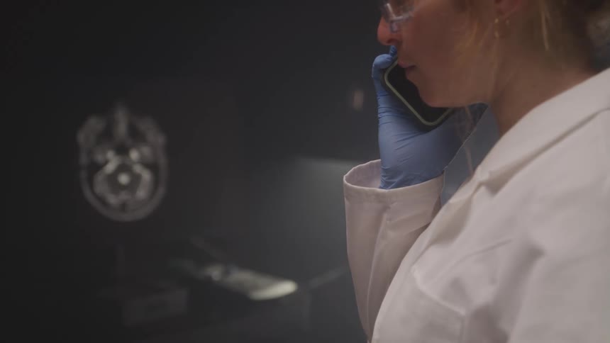 The woman is talking on her phone in the lab