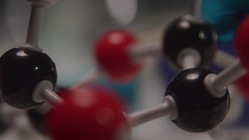 Molecular model with black and red spheres connected by white rods representing atoms and chemical bonds