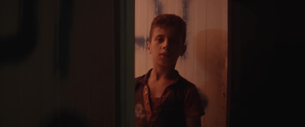 A boy stands in a dark doorway