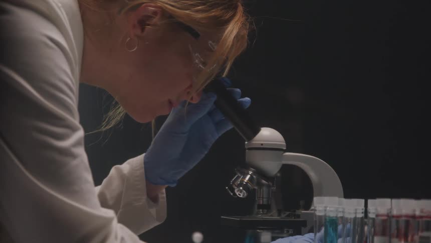 A scientist closely examines samples through a microscope in a laboratory