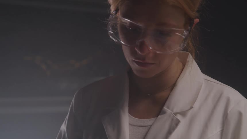 Female technician focuses while working in a dimly lit lab room