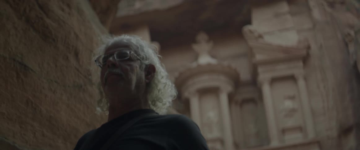 An older man walks away from an ancient edifice