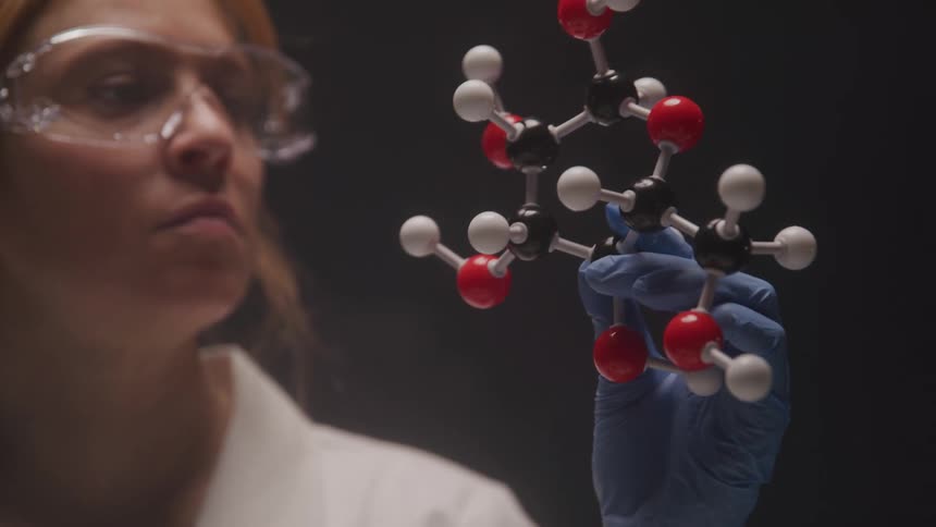 Woman with gloves in a laboratory picking up an object with molecules