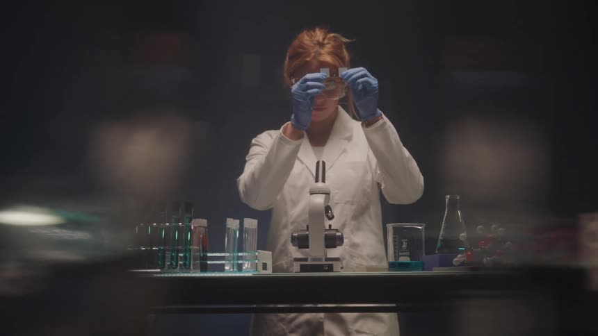Female scientist examines slide in lab