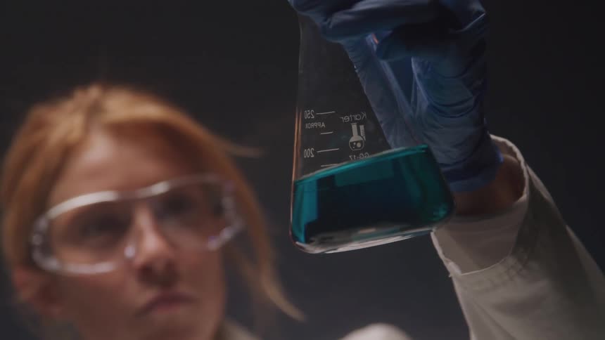 Girl in a laboratory observing a container with liquid