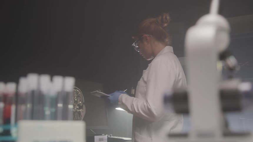 A worker in a white lab coat studies an xray in a scientific laboratory