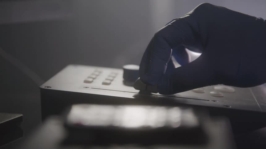 Gloved hand pressing a button on a device