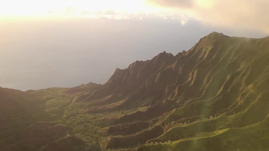 A mountainside is covered with ridges on a sunny day