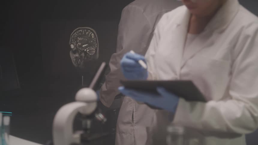 Researchers analyze brain scans in a laboratory using equipment and digital notes