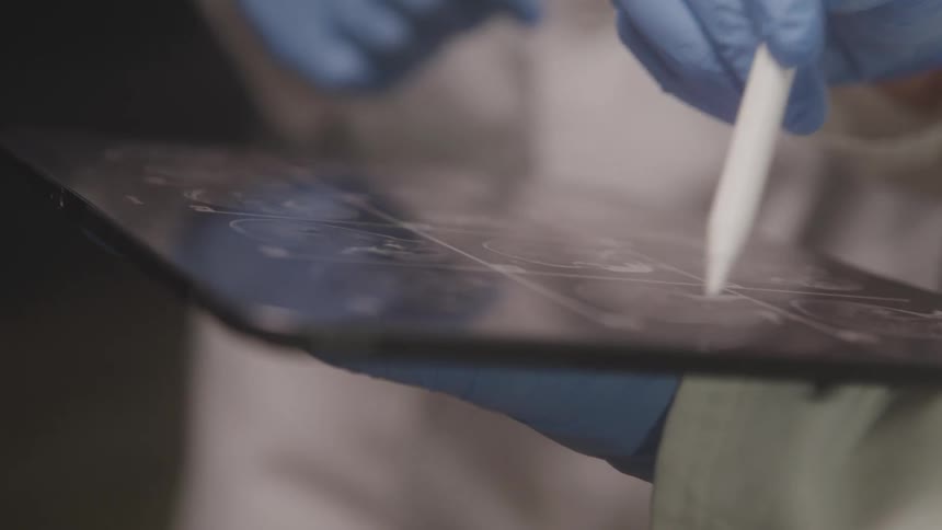 The video features a person wearing blue gloves indicating a medical or scientific setting they are using a stylus to interact with a transparent digital tablet on which some sort of diagram or data is visible