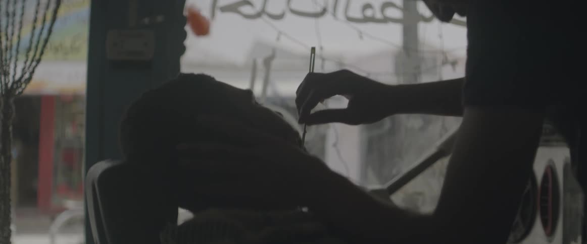 A barber gives a man a shave in a middle eastern city