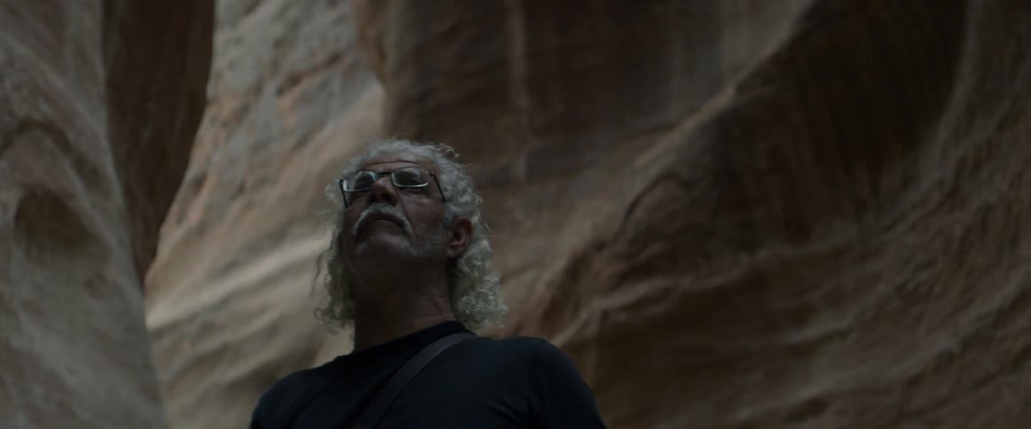 A man stands at the base of a canyon