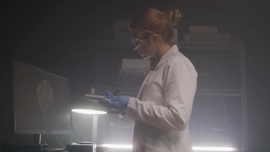 Woman in white coat recording data in a laboratory