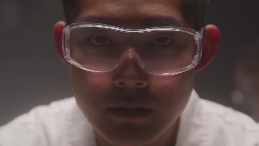 Male technician wearing safety glasses raises his head to stare