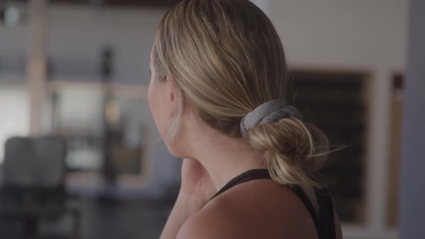 Close up portrait of a young woman making a phone call while sitting in the gym during daytime