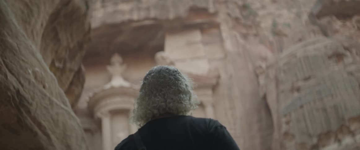 A man approaches a building that is carved into a canyon wall
