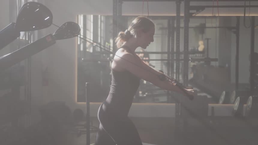 Woman trains on cable machine with focus in gym