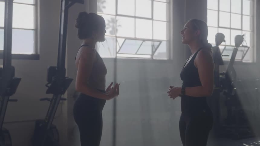 Two women talking to each other in a gym environment