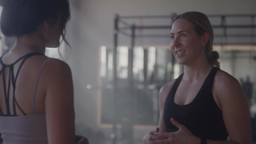 Two women talking in a gym space