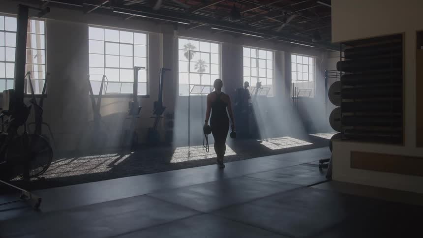 Woman walking through a gym with dumbbells
